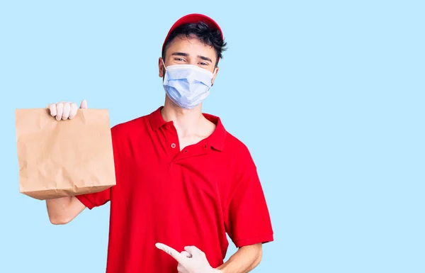 Teslimat Üniforması Giyen Sağlık Maskesi Takan Genç Spanyol Adam Elinde — Stok fotoğraf