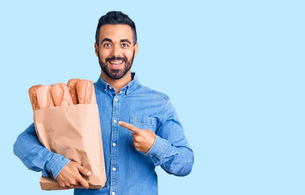 Jovem Hispânico Homem Segurando Saco Com Pão Sorrindo Feliz Apontando — Fotografia de Stock