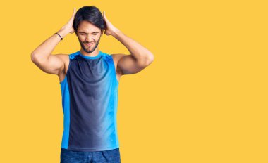 Spor kıyafetleri giyen yakışıklı İspanyol adam acı ve migren yüzünden çaresiz ve stresli. Eller başının üstünde.. 