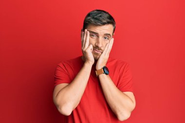 Yüzü, depresyonu ve üzüntüyü örten, gündelik kırmızı tişört giyen yakışıklı beyaz adam, sorun için üzgün ve sinirli. 