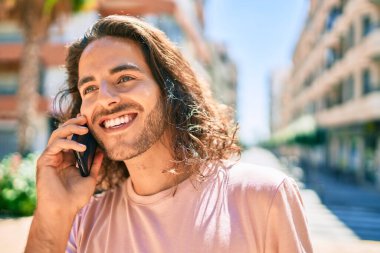 Genç İspanyol adam gülümsüyor. Şehirdeki akıllı telefondan konuşuyor..