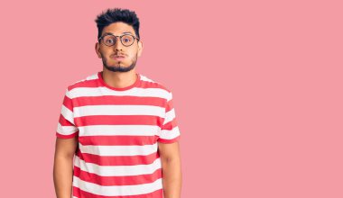 Yakışıklı Latin Amerikalı, sıradan kıyafetler giyen ve gözlüklü komik yüzlü, şişen yanaklı genç adam. Havayla şişmiş ağız, çılgın bir ifade.. 