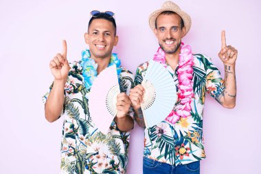 Yazlık tişört giyen, el ele tutuşan, gülümseyen, mutlu yüzlü iki genç gay. 