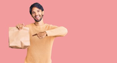 Yakışıklı İspanyol adam kağıt torbayı alıp götürüyor. Gülümsüyor, mutlu bir şekilde işaret ediyor. 