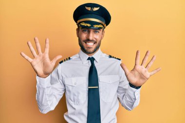 Yakışıklı İspanyol pilot üniforması giyen on numarayı gösterip işaret eden kendinden emin ve mutlu gülümseyen adam.. 