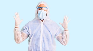 Doktor korumalı Coronavirus üniforması giyen genç İspanyol adam ve tıp maskesi başarıyı kutluyor. Kollarını kaldırıp, gözlerini kapayarak heyecanla bağırıyor. Kazanan konsept 