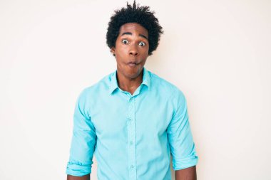Afro saçlı, sıradan kıyafetler giyen, dudaklı balık suratlı, çılgın ve komik jestler yapan yakışıklı Afro-Amerikan bir adam. Komik ifade. 