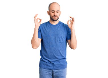 Gündelik tişört giyen genç yakışıklı adam rahatla ve gözleri kapalı gülümse parmaklarıyla meditasyon hareketi yapıyor. yoga konsepti. 