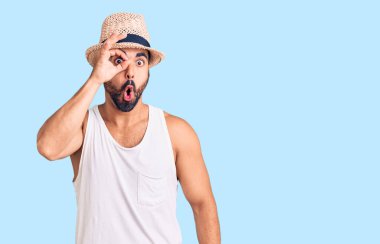 Gündelik yaz şapkası takan genç İspanyol adam şaşırmış yüz ifadesiyle şaşırmış, parmaklarından bakan gözler. İnançsız ifade. 
