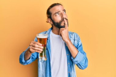 Uzun saçlı ve sakallı çekici bir adam. Yarım litre bira içiyor. Ciddi bir yüz ifadesi var. 