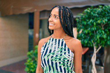 Genç Afrikalı Amerikalı kadın gülümseyerek şehirde mutlu mesut yürüyor..