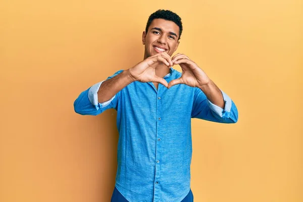 年轻的阿拉伯男子穿着休闲装 带着爱的笑容用手做心形符号 浪漫的概念 — 图库照片