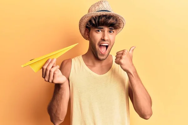 Joven Hispano Con Sombrero Verano Sosteniendo Avión Papel Apuntando Con — Foto de Stock