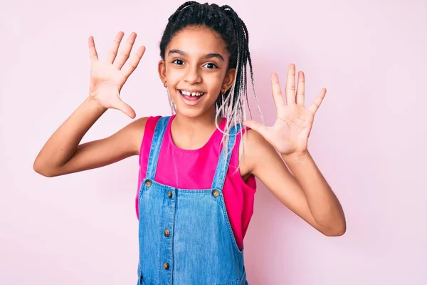 若いですアフリカ系アメリカ人の女の子子供とともにBraids身に着けていますカジュアル服上のピンクの背景表示と指摘指数10ながら笑顔自信と幸せ — ストック写真
