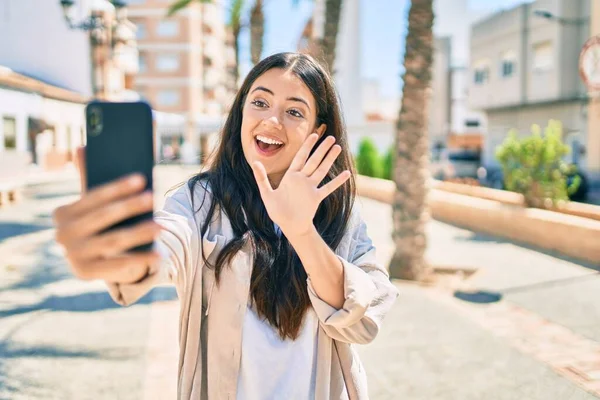 年轻的惊慌失措的女人高兴地笑着在城里用智能手机打了一个视频电话 — 图库照片