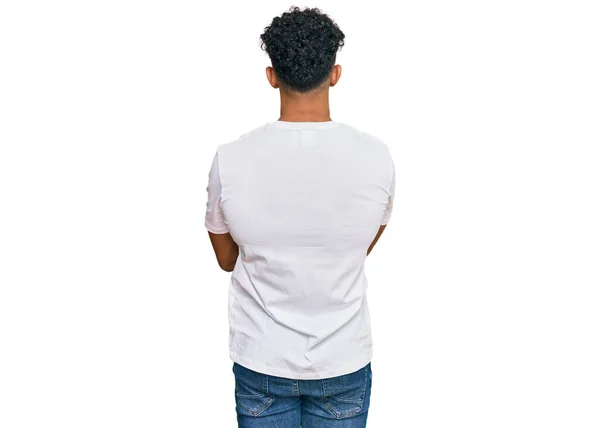 若いですArab男身に着けていますカジュアルホワイトTシャツ背を向けて立って離れて見ますとともに交差腕 — ストック写真