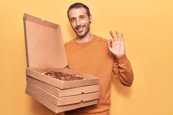 피자를 배달하는 잘생긴 남자가 손가락으로 글씨를 다정하게 미소짓고 있습니다 — 스톡 사진