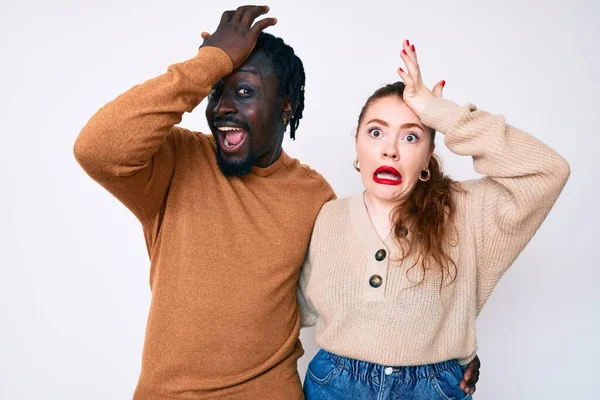 Interracial couple wearing casual clothes surprised with hand on head for mistake, remember error. forgot, bad memory concept.