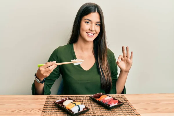 Joven Morena Comiendo Sushi Sentada Mesa Haciendo Signo Con Los — Foto de Stock