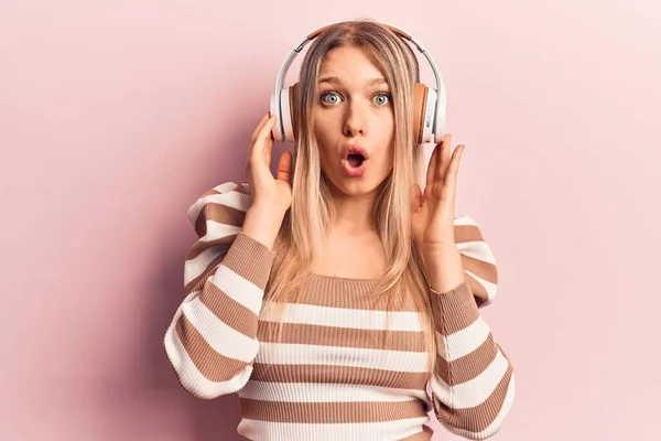 Młoda Blondynka Słuchająca Muzyki Przy Użyciu Słuchawek Przerażona Zdumiona Otwartymi — Zdjęcie stockowe