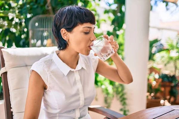 短い髪の美しい女性が晴れた日にテラスに座って新鮮な水を飲んで — ストック写真