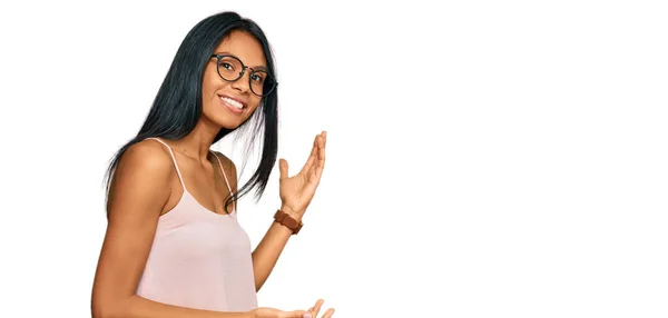 若いですアフリカ系アメリカ人女性を身に着けているカジュアル服や眼鏡をかけるために招待笑顔自然でオープン手 — ストック写真
