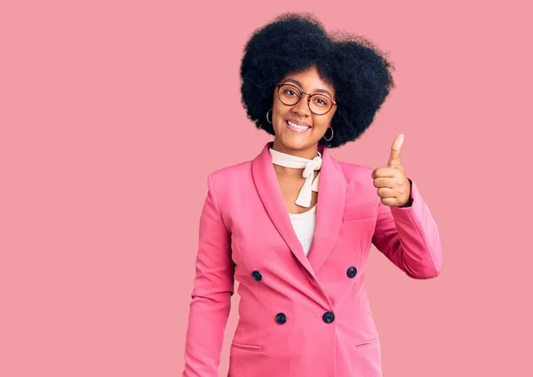 Young african american girl wearing business clothes and glasses smiling happy and positive, thumb up doing excellent and approval sign