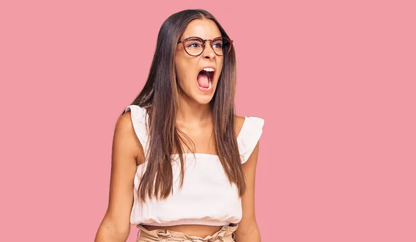 若いヒスパニック系の女性がカジュアルな服や眼鏡を着て怒りと怒りを叫び 怒りで叫んで怒っている 怒りと攻撃的な考え方 — ストック写真