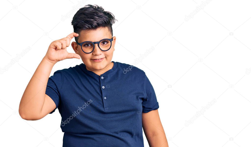 Little boy kid wearing casual clothes and glasses smiling and confident gesturing with hand doing small size sign with fingers looking and the camera. measure concept. 