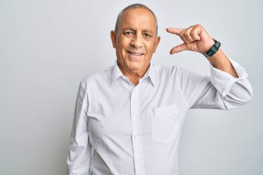 Yakışıklı, beyaz tişört giyen, gülümseyen, kendine güvenen, el hareketi yapan, küçük boy işareti yapan, parmaklarına bakan ve kameraya bakan bir adam. ölçüm kavramı. 