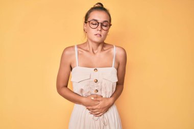 Güzel, beyaz bir kadın midesi üstünde yazlık elbise giyiyor çünkü hazımsızlık, acı verici bir hastalık kendini iyi hissetmiyor. Ağrı kavramı. 