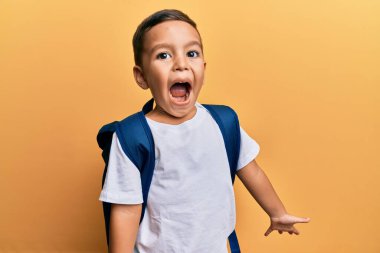 Komik suratlı sevimli Latin çocuk izole edilmiş sarı arka planda öğrenci çantası takıyor..