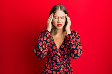 Güzel, genç, sarışın bir kadın. Elleri başının üstünde şık bir elbise giyiyor. Stres yüzünden baş ağrısı çekiyor. migren ağrısı. 