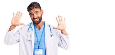 Doktor üniforması ve steteskop giyen İspanyol genç adam on numarayı gösterip işaret ederken kendinden emin ve mutlu gülümsüyor.. 
