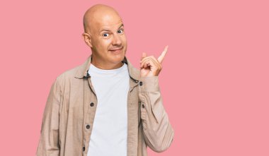 Orta yaşlı, kel, sıradan kıyafetler giyen, yüzünde kocaman bir gülümseme olan, elleri ve parmakları kameraya bakan bir adam.. 