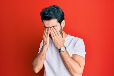 Günlük beyaz tişört giyen genç İspanyol adam yorgunluk ve baş ağrısı için gözlerini ovuşturuyor, uykulu ve yorgun bir ifade takınıyor. görme sorunu 