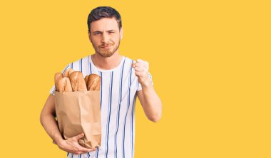 Elinde ekmek torbası olan yakışıklı genç bir adam öfkeyle bağırıyor, öfkeyle bağırıyor ve el kaldırıyor. 