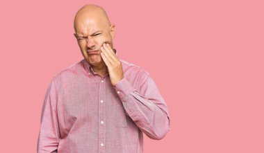 Orta yaşlı kel bir adam diş ağrısı ya da diş hastalığından dolayı ağzıyla acı dolu bir ifadeyle dokunuyor. dişçi 