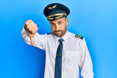 Sakallı, uçak pilotu üniforması giyen yakışıklı adam mutsuz ve sinirli görünüyor. Reddedilmiş ve olumsuz jestler yapıyor. kötü ifade. 