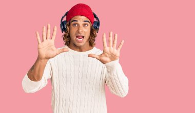 Kulaklık kullanarak müzik dinleyen genç İspanyol adam korku ifadesinden korkmuş ve dehşete düşmüş. El hareketlerini durdur, şok içinde bağır. panik konsepti. 