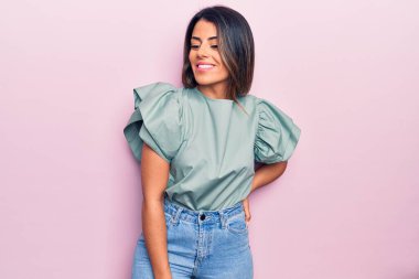 Genç ve güzel esmer kadın mutlu ve kendinden emin gülümsüyor. İzole edilmiş pembe arka planda yüzünde bir gülümsemeyle duruyorum.