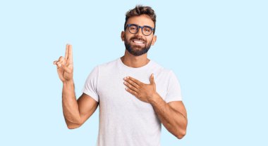 Gündelik kıyafetler ve gözlük takan genç İspanyol adam gülümsüyor. Göğsü ve parmakları havada küfür ediyor. Sadakat yemini ediyor. 