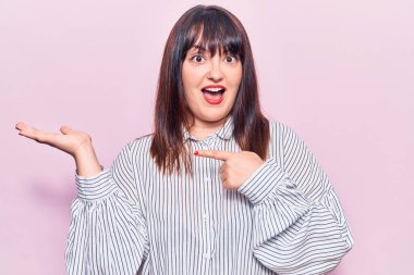 Genç ve cüsseli kadın gündelik giysiler giyip kameraya hayret ediyor ve gülümsüyor.. 