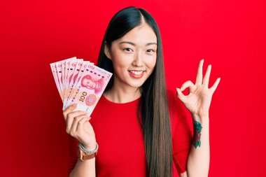 On yuan Çin banknotları tutan genç Çinli kadın parmaklarıyla imza atıyor, gülümseyerek mükemmel bir sembol oluşturuyor. 
