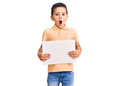 Küçük şirin çocuk elinde boş yeri olan karton bir afiş tutuyor. Korkmuş ve ağzı açık şaşkınlık içinde, inançsız bir yüz. 