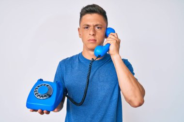 Antika telefon tutan genç İspanyol çocuk şüpheci ve gergin, sorun yüzünden surat asıyor. negatif kişi. 