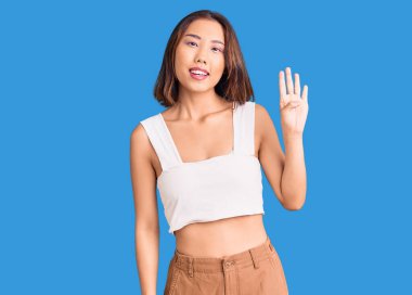 Genç, güzel Çinli kız, günlük giysiler içinde dört numarayı gösterip işaret ederken, kendinden emin ve mutlu bir şekilde gülümsüyor.. 