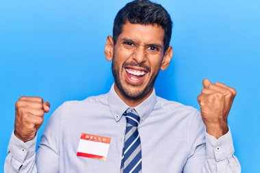 Merhaba yazılı çıkartma giyen genç latin adam benim adım gururla haykıran, zaferi ve başarıyı kutlayan kollarını kaldırarak heyecanlanan bir mesajdır. 