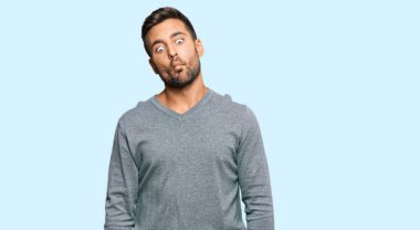 Yakışıklı, günlük kıyafetler giyen, dudaklarıyla balık suratı yapan, çılgın ve komik bir jest yapan bir İspanyol. Komik ifade. 