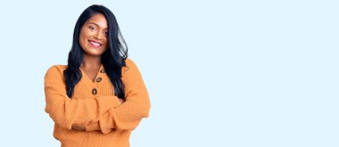 Uzun saçlı, sıradan bir kazak giyen, kollarını kavuşturup kameraya gülümseyen İspanyol bir kadın. pozitif kişi. 